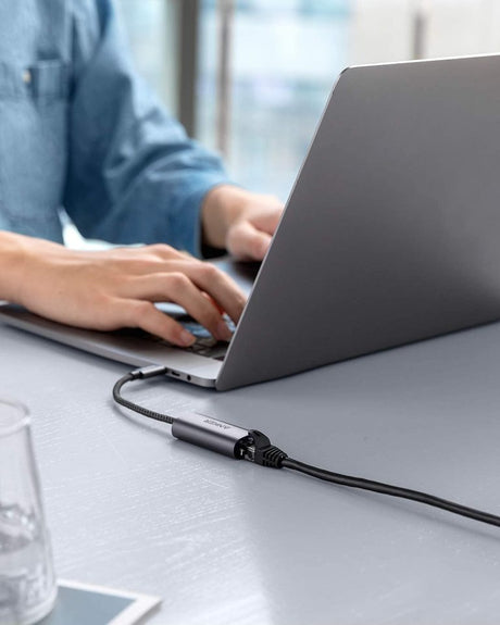 Anker PowerExpand USB-C to Gigabit Ethernet Adapter connected to a laptop, showing Ethernet port and compact design.